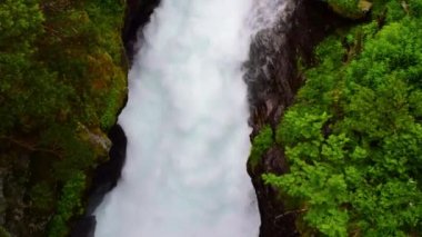 Slettafossen şelalesinin fırtınalı suları kayalarda bir kanal açmıştı. Yeşil ormanın Rocky yaz manzarası. Norveç.