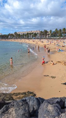 Playa de las Americas, Tenerife, İspanya - 7 Ocak 2025: İnsanlar geniş ve güzel kumlu sahillerde güneşlenip yüzüyor ve tatillerini Atlantik kıyısında geçiriyorlar..