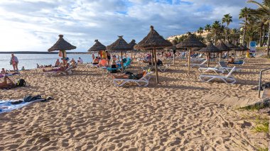Playa de las Americas, Tenerife, İspanya - 7 Ocak 2025: İnsanlar geniş ve güzel kumlu sahillerde güneşlenip yüzüyor ve tatillerini Atlantik kıyısında geçiriyorlar..