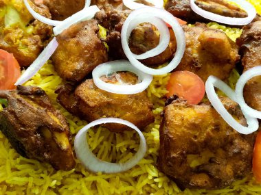 Geleneksel Biryani tavuğu Baharatlı sarı pirinç soğan halkaları ve domates dilimleriyle süslenmiş