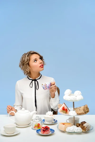 Portrait of young beautiful girl with sweets over blue background.