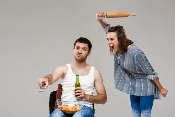 Young beautiful woman angering with man drinking beer, watching football.