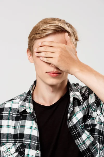 man covering eyes with hand