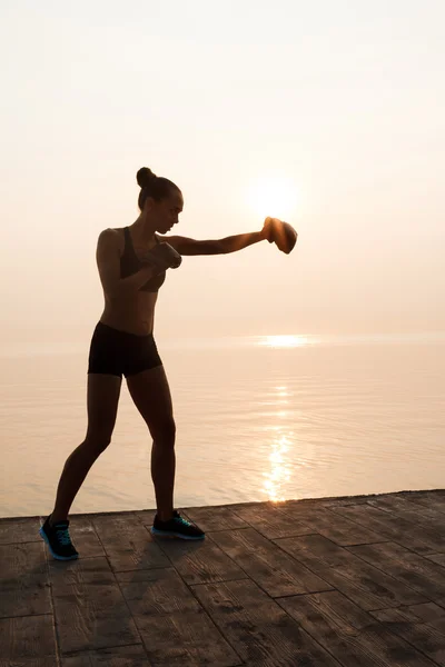 sportive girl training boxing at seaside