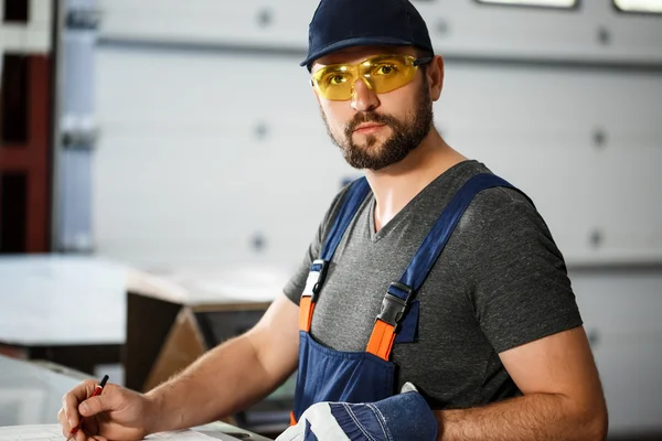 Portrait of worker in overalls, steel factory background.