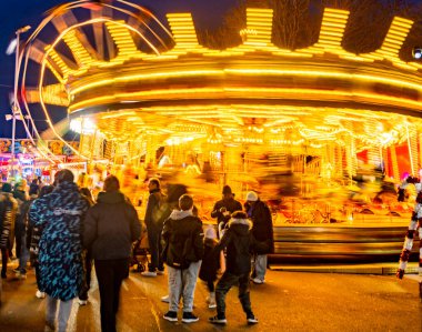Worcestershire, İngiltere-29 Kasım 2024: Kamu görevlileri Noel şenliği Viktorya Dönemi Fayre 'sinde atlıkarınca atları ve büyük tekerleklerle aydınlık lunapark gezilerinin keyfini çıkarıyorlar..