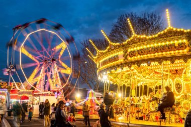 Worcestershire, İngiltere-29 Kasım 2024: Kamu görevlileri Noel şenliği Viktorya Dönemi Fayre 'sinde atlıkarınca atları ve büyük tekerleklerle aydınlık lunapark gezilerinin keyfini çıkarıyorlar..
