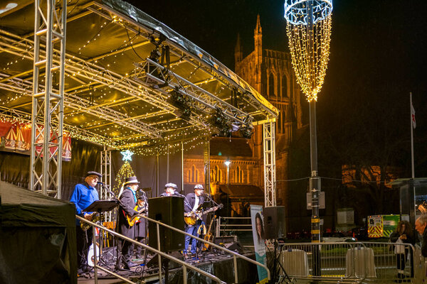 Worcestershire,England-November 29 2024: A local band plays on a temporary stage set up, in Cathedral square,opposite the historic landmark in the early evening,during the build up to Christmas.