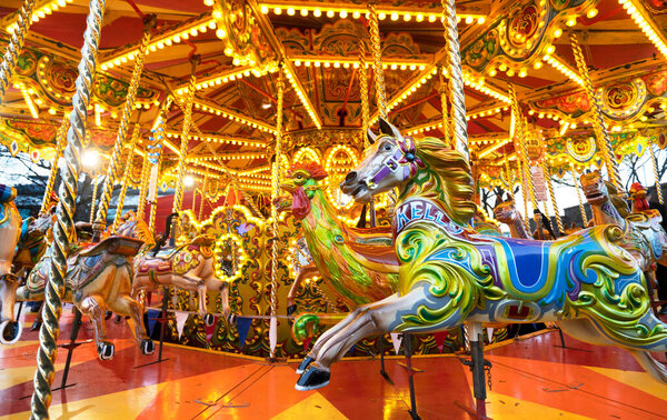 Worcestershire,England-November 29 2024: Colorfully lit funfair ride with carousel horses spinning round,part of the Victorian Fayre entertainment and fun attractions leading up to Christmas.