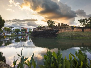 Güzel şehir manzarası ve arka plandaki tarihi hendekteki bulutların yansımaları, güzel, pitoresk ağaçlar ve çiçekler güneş batarken suların kenarında..