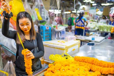 Thailand-January 25 2025:A female worker prepares religious floral offerings for sale,inside Pak Khlong Talat,the primary flower market of Bangkok,known for its stunning fresh flower displays.