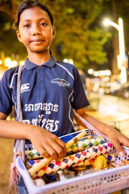 Siem Reap, Kamboçya-02 Nisan 2025: Şehrin gece hayatı bölgelerinde, çocuklar sokaklarda dolaşıp, hediyelik eşya satmaya çalışıyor, ailelerine para getiriyor, onlar da onları para kazanmaya gönderiyorlar..