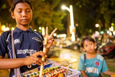 Siem Reap, Kamboçya-02 Nisan 2025: Şehrin gece hayatı bölgelerinde, çocuklar sokaklarda dolaşıp, hediyelik eşya satmaya çalışıyor, ailelerine para getiriyor, onlar da onları para kazanmaya gönderiyorlar..