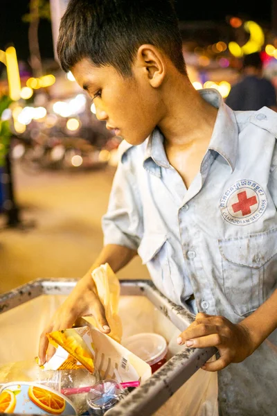 Siem Reap, Kamboçya-02 Nisan 2025: Şehrin sokaklarında, fakir genç bir çocuk, halka açık bir çöp toplama konteynırında değerli eşyalar arıyor..