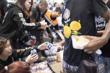 Bangkok-26 Nisan 2025: Günbatımında, AAS Metro Bangkok bisikletçileri bölümü üyeleri yoksullara ihtiyaç duyulan gıdaları dağıtmaya geliyor..