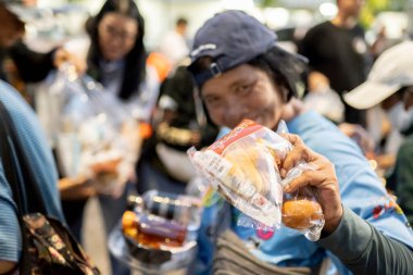 Bangkok-26 Nisan 2025: Günbatımında, AAS Metro Bangkok motorcular bölümü üyeleri yoksullara ihtiyaç duyulan gıdaları dağıtmaya geliyor..