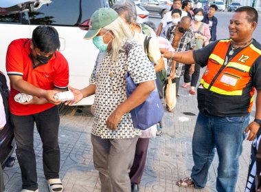 Bangkok-26 Nisan 2025: Her gün gün batımında insanlar araçların arkasından yoksullara yiyecek dağıtmak için geliyorlar. Salgın sonrası şehirde yaşayan evsiz insan sayısı arttı..