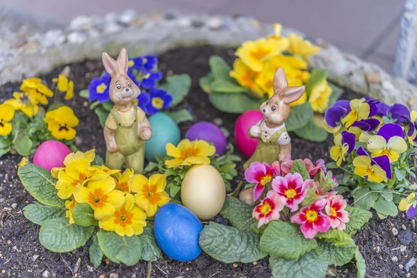 Huevos coloridos de Pascua en una maceta con flores violetas con cuernos —  Fotos de Stock