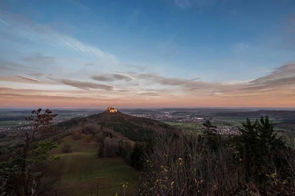 Sunrise at Zeller Horn with view to medieval knight castle Burg Hohenzollern with beautiful colored clouds in the sky in autumn in Bisingen Hechingen, Germany