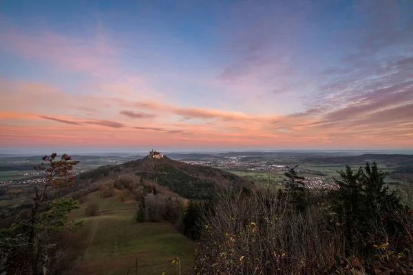 Sunrise at Zeller Horn with view to medieval knight castle Burg Hohenzollern with beautiful colored clouds in the sky in autumn in Bisingen Hechingen, Germany