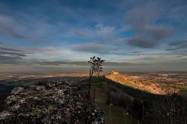 Sunrise at Zeller Horn with view to medieval knight castle Hohenzollern with rock stone and pine tree and sun rays in Bisingen Hechingen, Germany