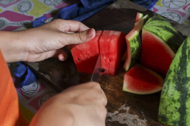 Keskin bir bıçakla taze, kırmızı, sulu karpuz meyvelerini doğrayarak. Odaklanma anı yemek hazırlama sağlıklı, tatlı atıştırmalıklar yaratma