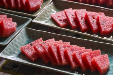 Yeşil tabağa dizilmiş lezzetli kırmızı karpuz dilimi. Serin, sulu, sağlıklı meyve tatlısı yaz atıştırmalıkları veya parti için mükemmel, ferahlatıcı ve tatlı yiyecekler.