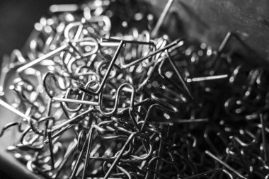 Metal klipslerin dağınık siyah beyaz arka planı. Bu zımbalar atölyede ya da garajda plastik kaynakçı olarak kullanılır.