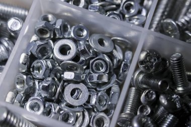 Close up of large assortment of metal and steel hardware. variety of nut, bolt, washer, and screw fasteners neatly arranged inside plastic box container organizer