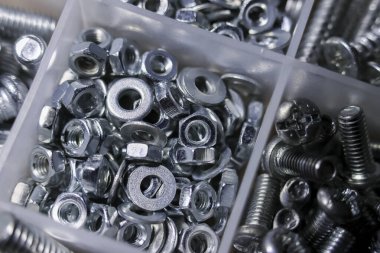 Close up of large assortment of metal and steel hardware. variety of nut, bolt, washer, and screw fasteners neatly arranged inside plastic box container organizer
