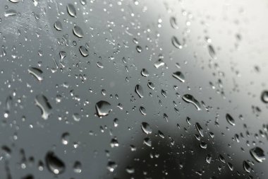 Penceresinde saf su damlaları olan nemli camların kasvetli ve soyut arkaplanı. Huysuz, melankolik doku gri, yağmurlu günü yansıtır, berrak bir yoğunluk ve sakin bir duyguyla.