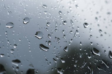 Camdaki birçok yağmur damlasının kasvetli görüntüsü. Su damlalarıyla soyut bir arkaplan yüzeyde kasvetli bir doku oluşturuyor. Gri, yağmurlu bir günde, nemli bir hava.