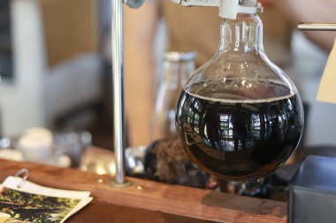 Koyu kahveyle doldurulmuş cam kahve üreticisi. Konforlu kafe içindeki ahşap tezgahta zanaatkar hazırlığı. Keyifli deneyimler arayan içki meraklıları için davet edici atmosfer