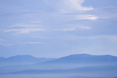 Sakin bir manzara, uzak dağ örtülü, yumuşak mavi bir sis ile ortaya çıkar. Yumuşak bulutlar, huzurlu bir atmosfer yaratarak, sakin gökyüzünde sürükleniyor. Doğal manzara sessiz yalnızlığı çağrıştırıyor.