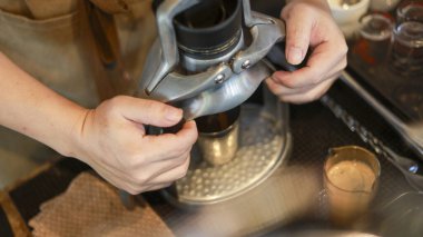 Odaklanmış kahve ustası el değirmeniyle taze kahve hazırlıyor. Rahat bir kafede ya da kafede profesyonel ekipmanlarla sabah espresso içeceği hazırlama süreci