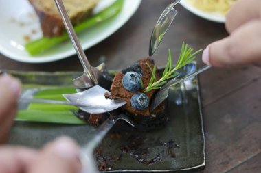 Tatlı çikolatalı tatlıyı çatal ve kaşıkla paylaşan insanlara yakın durun. Taze yaban mersinli ve biberiyeli browni Birlikte nefis bir an