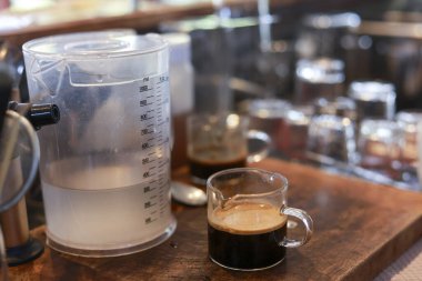 Kırsal ahşap tepside kremalı taze espresso kahvesi. İçmek için sıcak suyu olan temiz su ısıtıcısı sıcak kafe ortamının yanında oturur.