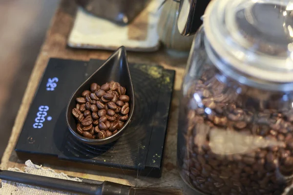 Profesyonel barista hazır olması için dijital ölçekte taze kavrulmuş kahve çekirdeği tartıyor. Kaliteli içecek için Cafe 'de hassasiyetle ölçülen Aromatik Arabica bileşeni