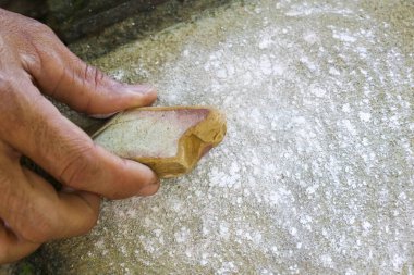 Zanaatkar el özenle ham mücevheri tutar, pürüzlü yüzeyde dikkatlice öğütür. Bu odaklanmış, geleneksel süreç lapidary ve el yapımı mücevher yapma sanatını vurguluyor