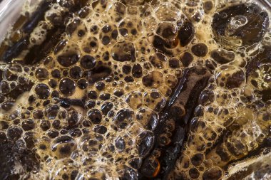 Fermantasyon sırasında kahverengi sıvının soyut arkaplan dokusunu kapat. Organik gıda süreci köpüklü kabarcıklar yaratır, bu da içecek için ilginç bir şablon oluşturur.