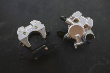 Hidrolik disk sistemi için gümüş motorsiklet fren kalibreli parça. Araç güvenliği için gerekli olan bu mekanik bileşen, tamir için siyah arkaplanda izole edilmiş.