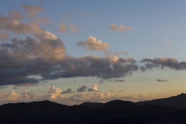 Sakin dağ silueti alacakaranlıkta güzel mavi gökyüzüne karşı. Gün batımındaki renkli bulutların huzurlu manzarası sakin ve sakin bir açık hava manzarası yaratıyor.