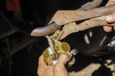 Odaklanmış tamirci, kerpetenle motor fren kalibresini kapatarak tamir ediyor. Garaj atölyesinde konsantrasyonla el işi yaparken kapatıyoruz.