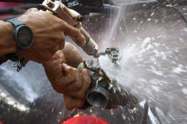 Odaklanmış işçi endüstriyel bakım yapıyor, metal parçalarını temizlemek için yüksek basınçlı su tabancası kullanıyor. Güçlü sprey kiri yoğun güç ve hassasiyetle temizler.