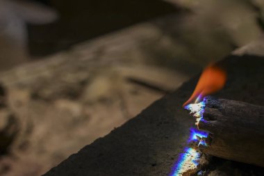 Yanan odunların yoğun sıcaklığı mavi ve turuncu alevlere yakın olduğunu gösteriyor. Yanma ve ham enerjinin bu güçlü ayrıntısı ateşin soyut arkaplanını oluşturur.