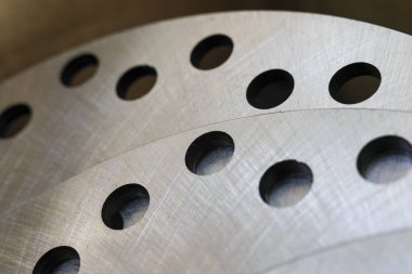 Metal diskin endüstriyel arka planını delinmiş delikle kapatın. fırçalanmış çelik dokusu otomotiv makinelerinde güç ve hassasiyet duygusunu iletir