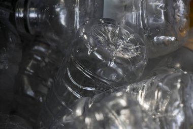 Boş, şeffaf plastik şişe atığı yığınına yakından bakmak, geri dönüşüm ve çevre kirliliği sorununu temsil ediyor. Çöpe atılmış konteynırların arkaplanı