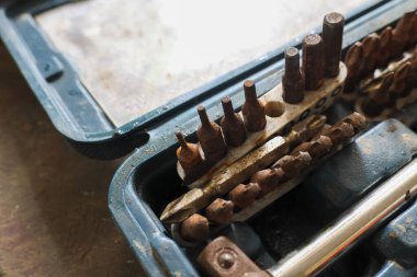 Matkap ve tornavidayla eski paslı alet seti kirli mavi alet kutusunu ısırdı. Tamir ve bakım için atölyedeki paslanmış metal ekipmanlarının ihmal edilmiş koleksiyonu
