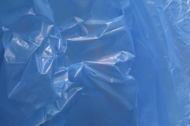Buruşuk ve buruşuk dokusu olan soyut mavi plastik arka plan. Bu parlak yaprak yüzeyi çeşitli tasarım kavramları için ayrıntılı ve ilginç desenler sunar