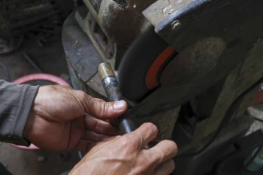 Atölyede makineli aletle metal öğüten konsantre bir işçi. Ustabaşı, tamirat için çelik ve elektrikli aletlerle çalışmaya odaklandı